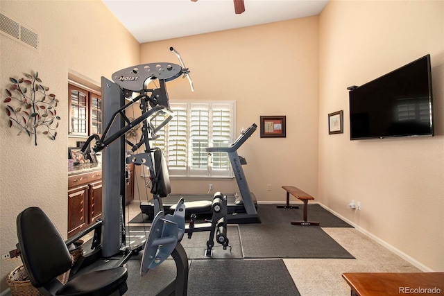 workout room featuring ceiling fan, carpet, and vaulted ceiling