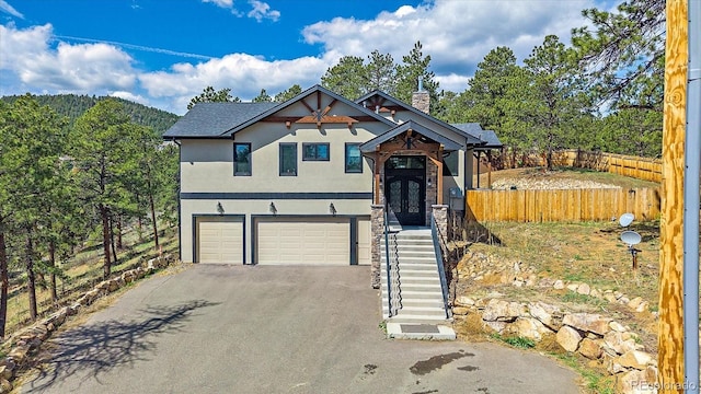 view of front of home featuring fence, driveway, a garage, stucco siding, and a chimney