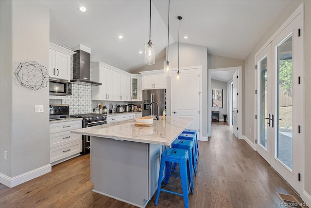24701 US Highway 40, Golden, CO 80401 - kitchen featuring high quality appliances, wall chimney range hood, lofted ceiling, a kitchen island with sink, and baseboards