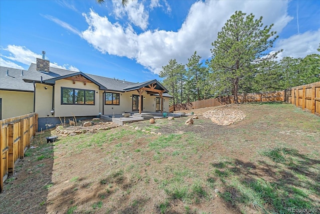 24701 US Highway 40, Golden, CO 80401 - rear view of house with a fenced backyard, a patio area, stucco siding, and a chimney