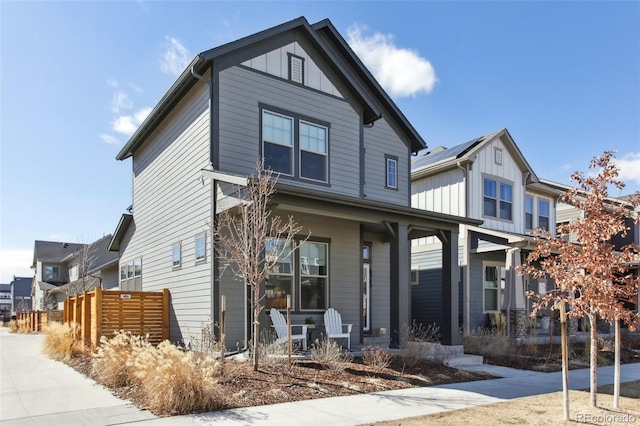 view of front of house with a porch, board and batten siding, and fence