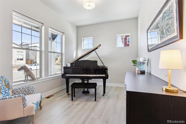 living area with baseboards, visible vents, and wood finished floors