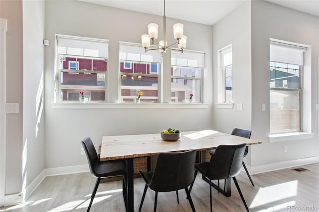 dining space with an inviting chandelier, visible vents, baseboards, and wood finished floors