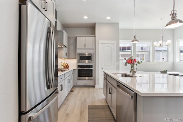 kitchen featuring pendant lighting, light wood finished floors, recessed lighting, appliances with stainless steel finishes, and a sink