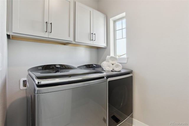 washroom featuring cabinet space and washer and clothes dryer