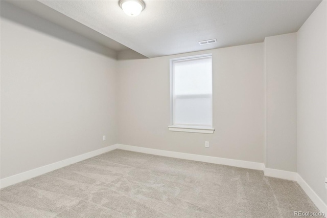 spare room featuring a textured ceiling, carpet, visible vents, and baseboards