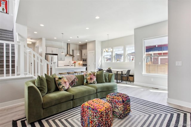 living room with stairs, recessed lighting, light wood-type flooring, and a notable chandelier