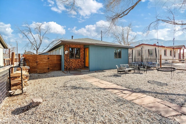 back of house with a mountain view, a fire pit, and a trampoline