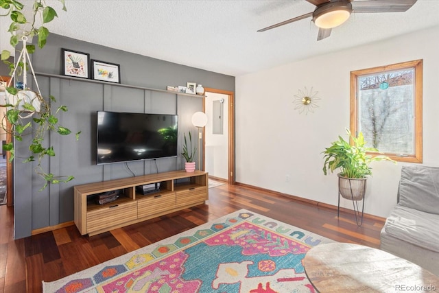 living room featuring ceiling fan, dark hardwood / wood-style flooring, and a textured ceiling