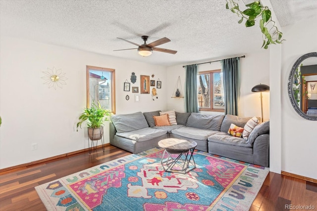 living room featuring dark wood-type flooring, a textured ceiling, and ceiling fan