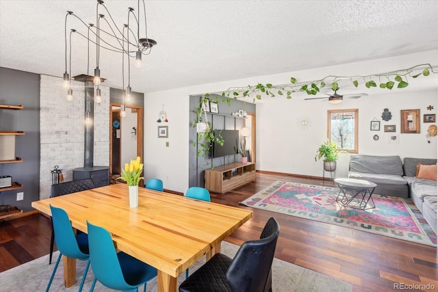 dining space with ceiling fan, hardwood / wood-style floors, a textured ceiling, and a wood stove