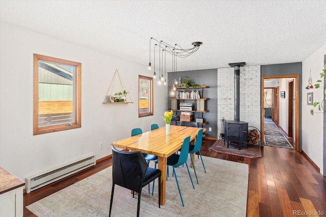 dining room with dark hardwood / wood-style flooring, a wood stove, a textured ceiling, and baseboard heating