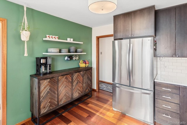 kitchen featuring tasteful backsplash, stainless steel fridge, hardwood / wood-style floors, and dark brown cabinets