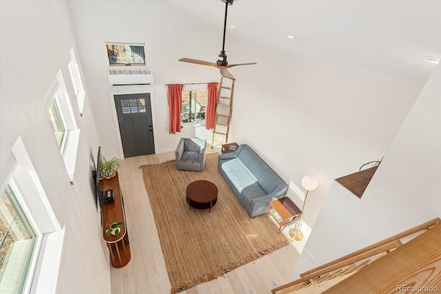 living room with hardwood / wood-style flooring, ceiling fan, an AC wall unit, and high vaulted ceiling