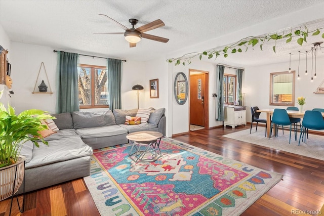 living room featuring ceiling fan, dark hardwood / wood-style floors, and a textured ceiling