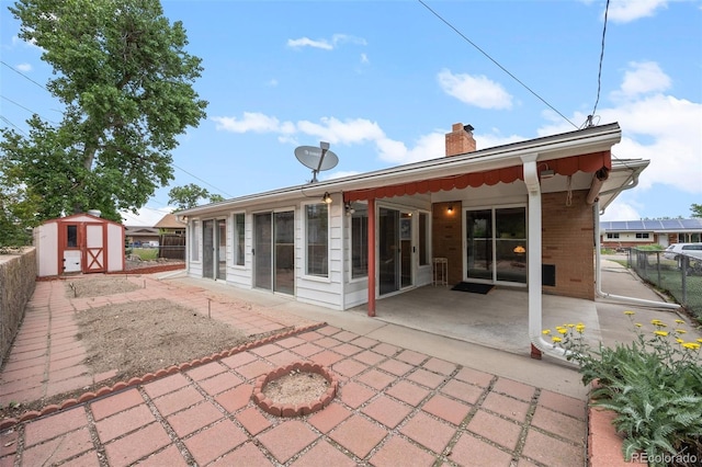 8205 Pennsylvania St, Denver, CO 80229 - rear view of property with a patio, a storage shed, a chimney, and brick siding