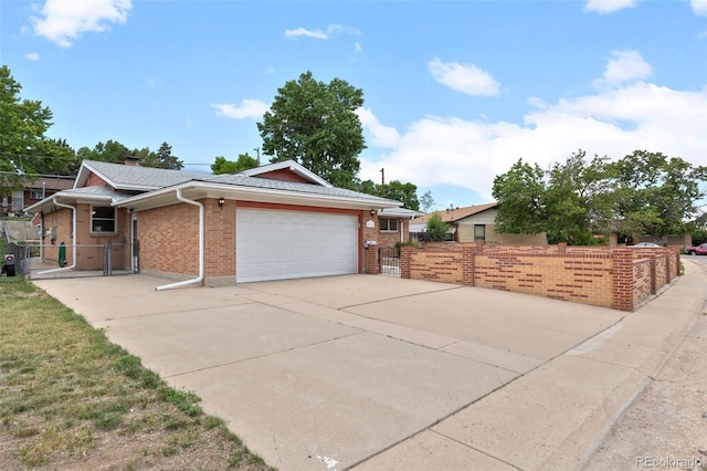 8205 Pennsylvania St, Denver, CO 80229 - view of front of home featuring an attached garage, brick siding, a gate, and driveway
