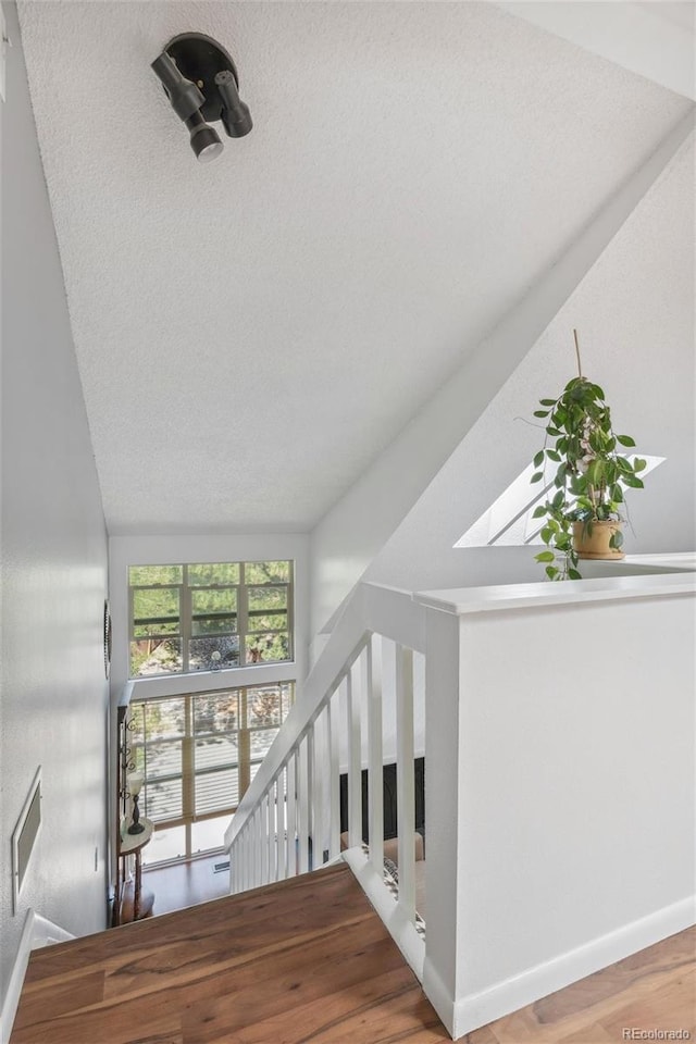 701 Harlan St Unit E29, Lakewood, CO 80214 - staircase with a textured ceiling, baseboards, and wood finished floors