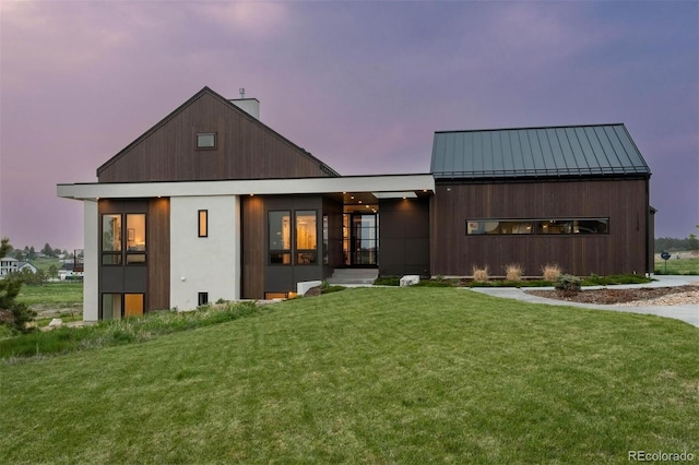 back house at dusk with a lawn