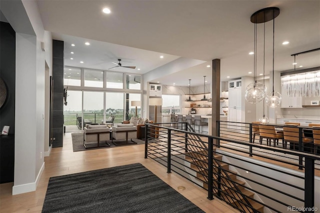 interior space featuring ceiling fan, light hardwood / wood-style flooring, and a wall of windows