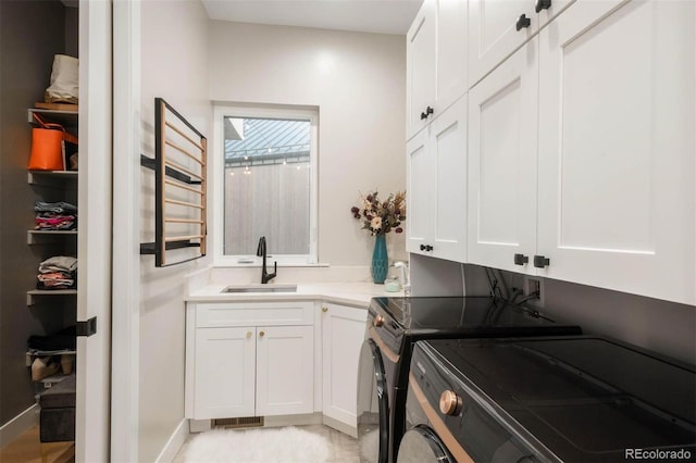 washroom featuring washer and dryer, sink, and cabinets