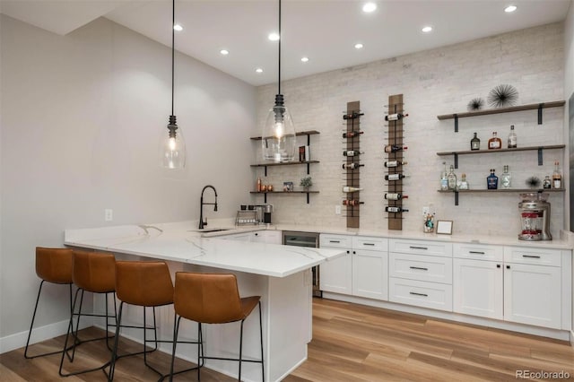 bar featuring sink, tasteful backsplash, light stone counters, pendant lighting, and white cabinets