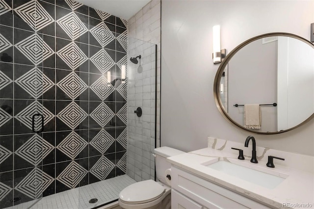 bathroom with a tile shower, vanity, and toilet