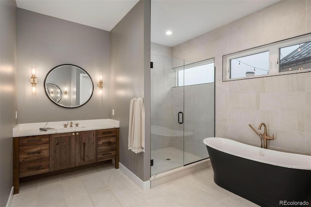 bathroom with a freestanding tub, a stall shower, vanity, and tile patterned flooring