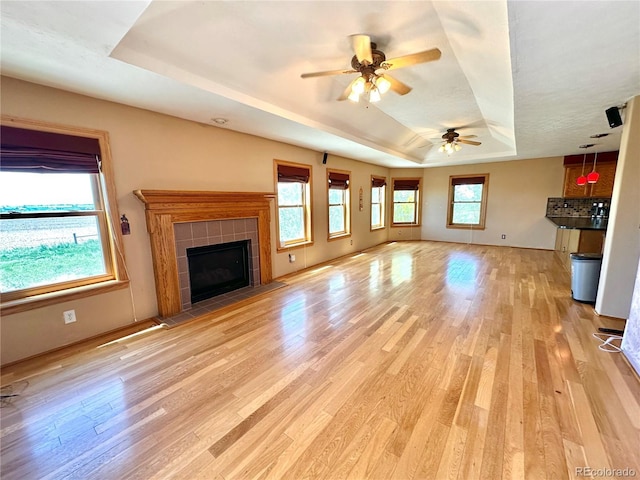 24938 County Road 18, Keenesburg, CO 80643 - unfurnished living room with a raised ceiling, light wood finished floors, ceiling fan, and a tiled fireplace