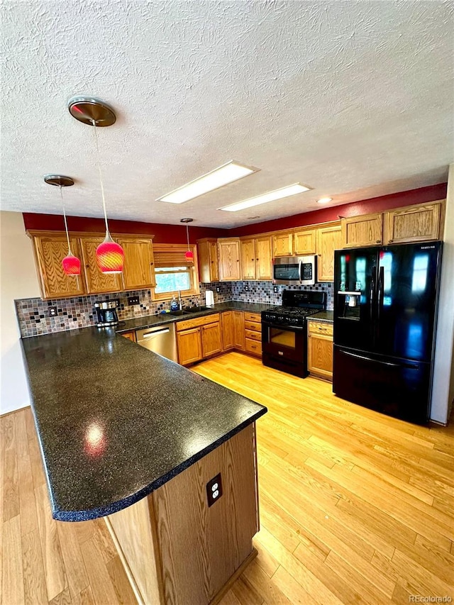 24938 County Road 18, Keenesburg, CO 80643 - kitchen featuring black appliances, a peninsula, dark countertops, light wood finished floors, and a textured ceiling