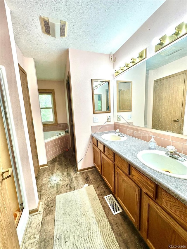 24938 County Road 18, Keenesburg, CO 80643 - bathroom featuring wood finished floors, double vanity, a bath, tasteful backsplash, and a textured ceiling