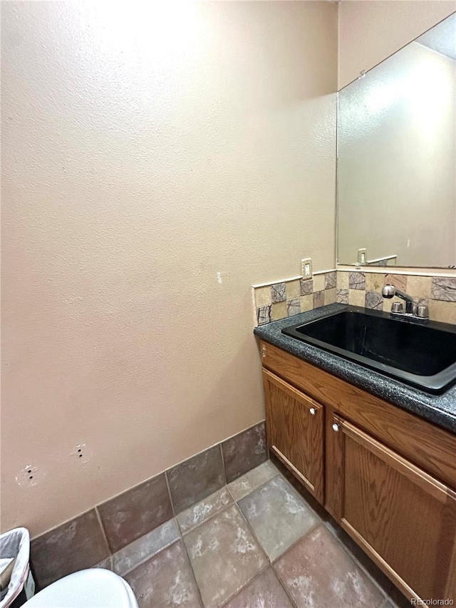 24938 County Road 18, Keenesburg, CO 80643 - half bathroom with stone tile floors, vanity, tasteful backsplash, and toilet