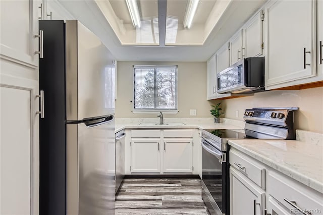 kitchen with sink, light hardwood / wood-style flooring, white cabinets, and appliances with stainless steel finishes