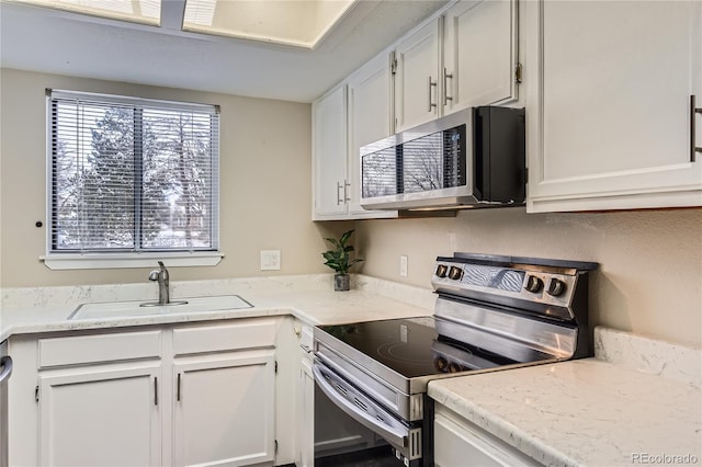 kitchen with stainless steel appliances, sink, white cabinets, and light stone counters