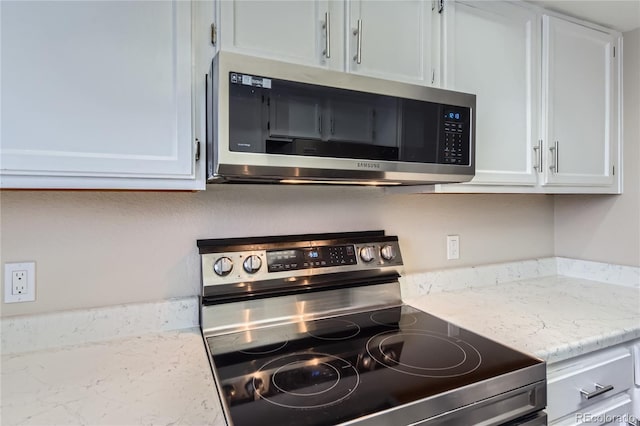 kitchen with light stone counters, white cabinets, and appliances with stainless steel finishes