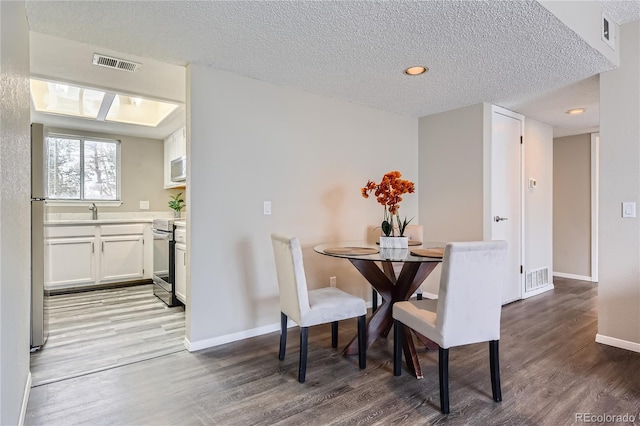 dining room featuring sink, hardwood / wood-style floors, and a textured ceiling