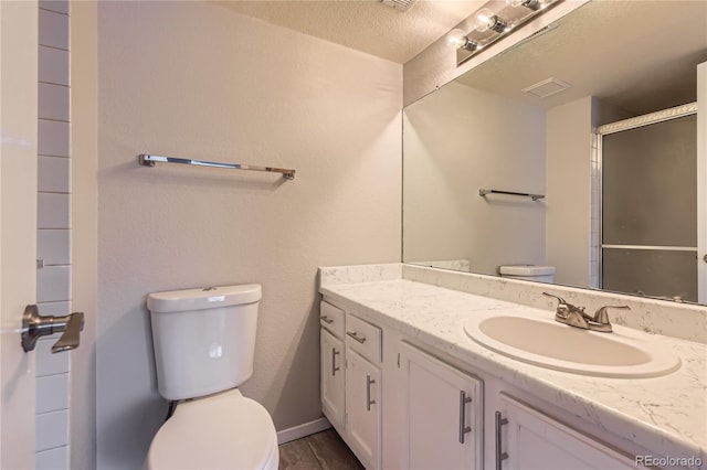 full bath featuring vanity, visible vents, a shower with shower door, a textured ceiling, and toilet