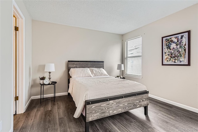 bedroom with dark wood-style floors, a textured ceiling, and baseboards