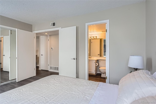 bedroom with ensuite bathroom, sink, a textured ceiling, dark hardwood / wood-style floors, and a closet