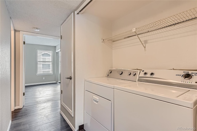 clothes washing area featuring washer and dryer, a textured ceiling, dark wood finished floors, baseboards, and laundry area