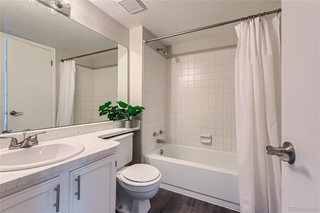 full bathroom featuring hardwood / wood-style flooring, shower / tub combo, vanity, a textured ceiling, and toilet