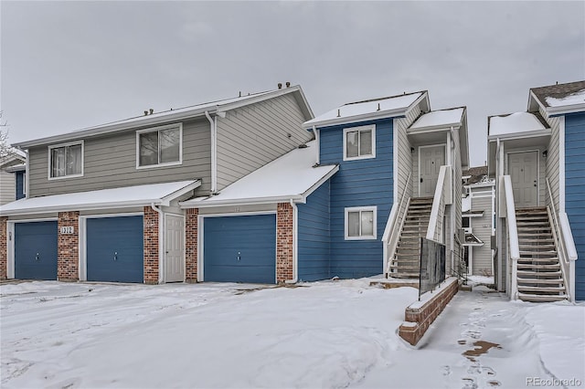 townhome / multi-family property with stairs, a garage, and brick siding