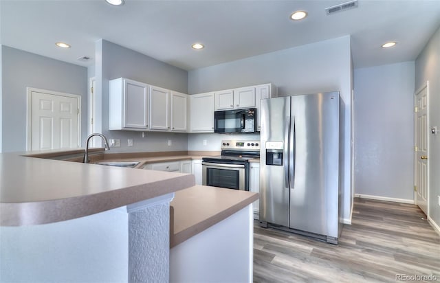17205 Waterhouse Cir Unit C, Parker, CO 80134 - kitchen with appliances with stainless steel finishes, a peninsula, white cabinetry, recessed lighting, and light wood finished floors
