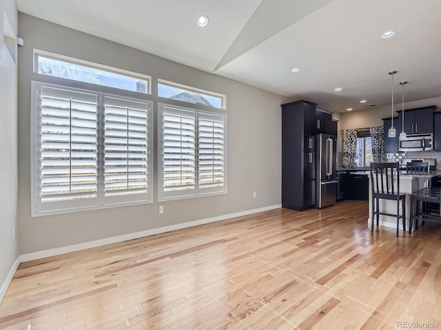 living room featuring a healthy amount of sunlight, vaulted ceiling, and light wood-type flooring