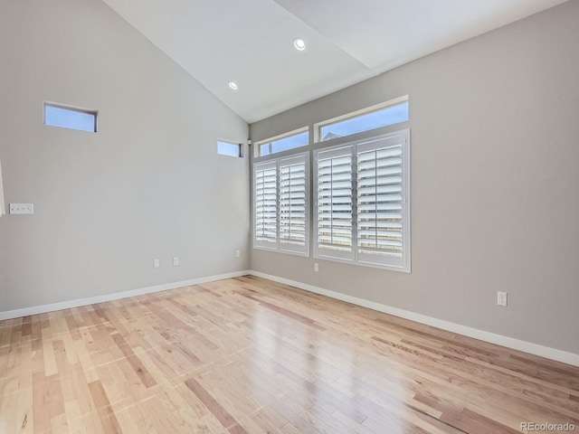 empty room featuring high vaulted ceiling and light hardwood / wood-style flooring