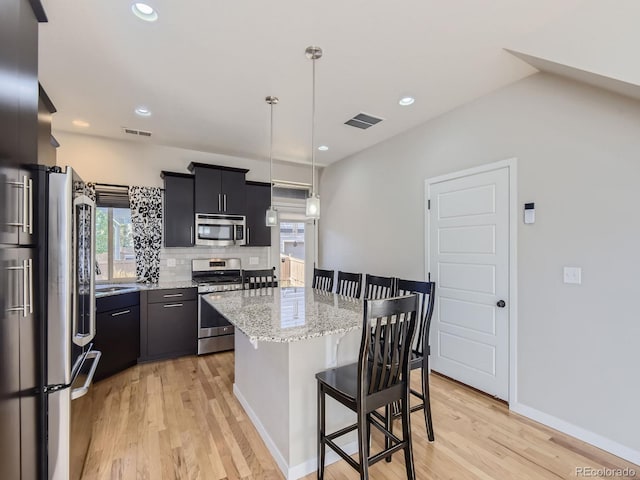 kitchen with light hardwood / wood-style floors, a center island, hanging light fixtures, and appliances with stainless steel finishes