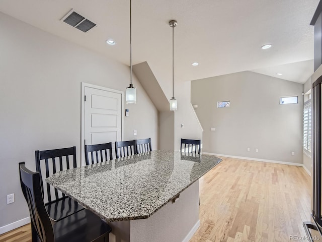 interior space featuring light stone counters, decorative light fixtures, vaulted ceiling, and light wood-type flooring