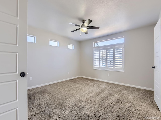 carpeted spare room featuring ceiling fan and a healthy amount of sunlight