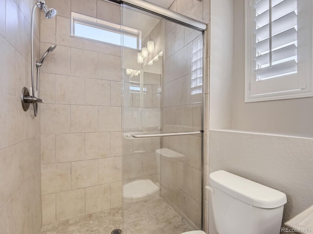 bathroom featuring toilet and a shower with door