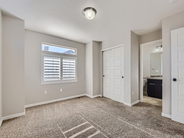 unfurnished bedroom with ensuite bath, a closet, and carpet